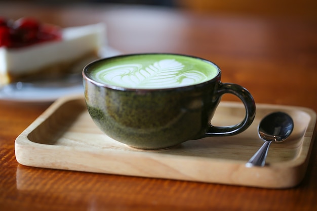 Hete groene theematcha latte in kop op lijst.