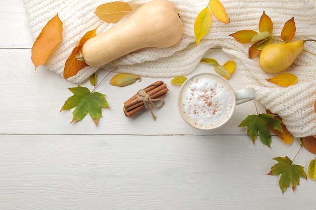 Hete herfst drink koffie of cacao met gele bladeren en decoratieve pompoenen op een witte houten tafel herfst compositie bovenaanzicht