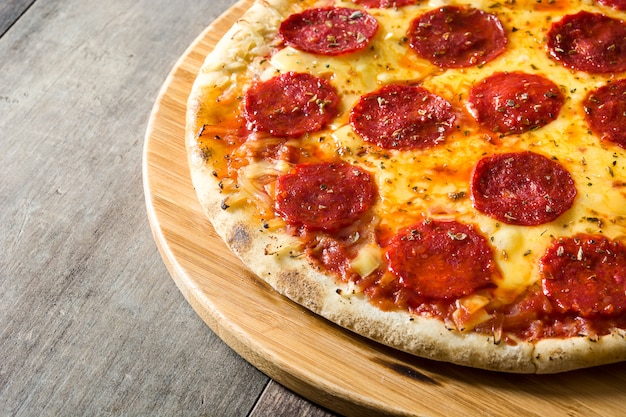 Hete Italiaanse pepperonispizza op houten lijst