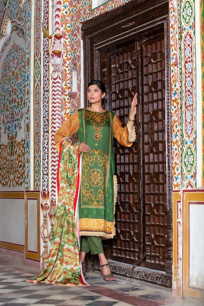 Hete jonge meid poseert voor traditionele fotoshoot op een prachtige oude plek in Desi-jurk