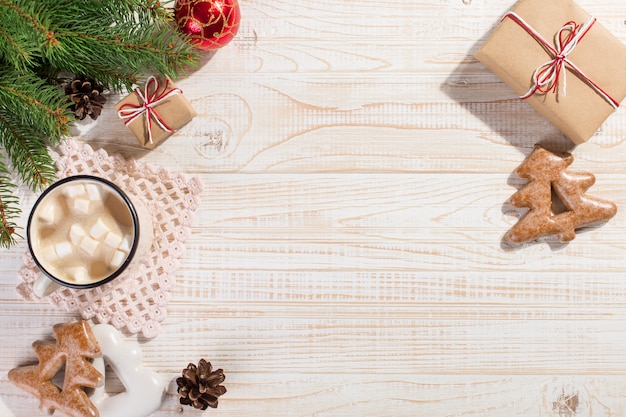 Hete kerstdrank met marshmallows in een ijzeren mok en peperkoekkoekjes, op een witte tafel. , vakantie, copyspace.