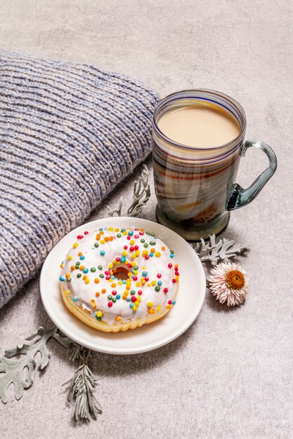 Hete koffie met een donut. Winterdrank voor een goed humeur met trui, bladeren en bloemen.