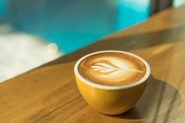 Hete kunst Latte-Koffie in een kop op houten lijst en ochtendlicht