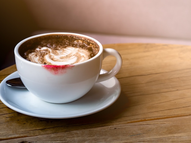 Hete latte met lattekunst in witte koffiekop met de vlek van de rode kleurenlippenstift