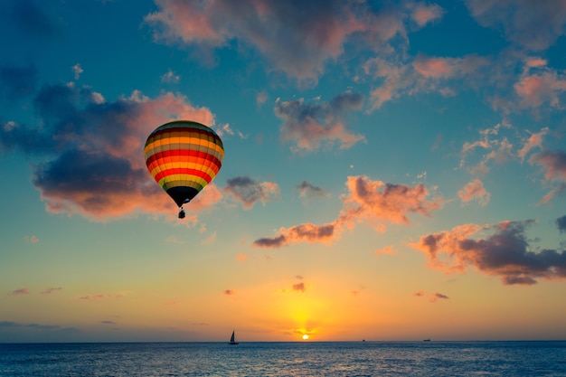 Hete luchtballon met zonsondergang op de achtergrond van de zee