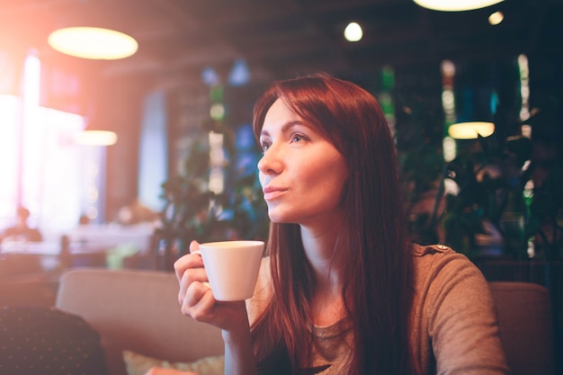 Hete mok thee met vrouwenhanden. mooie vrouw met kopje koffie op het restaurant