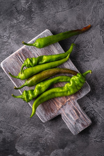 Hete pittige groene chilipepers op houten snijplank, steenbeton