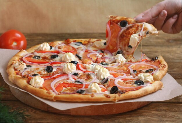 Hete pizza met kaas, tomaten, uien en olijven op een houten bord In de buurt zijn tomaat en dille