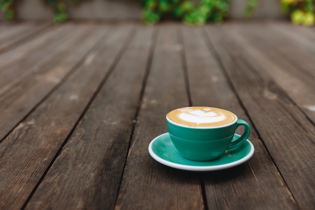 Hete smakelijke aromacappuccino met weelderig melkschuim in mooie groen gekleurde kop geserveerd op schotel
