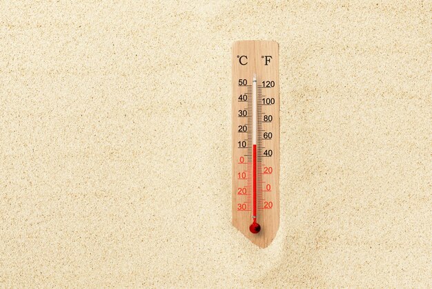 Hete zomerdag Celsius en Fahrenheit schaalthermometer in het zand Omgevingstemperatuur plus 12