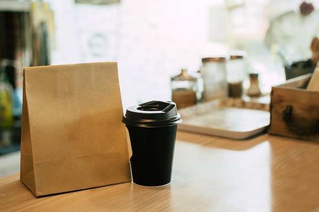 Hete zwarte koffiekop en dessertpapier set tas wachten op klant op balie in moderne café coffeeshop, eten bezorgen, café restaurant, afhaalmaaltijden, kleine ondernemer, eten en drinken concept