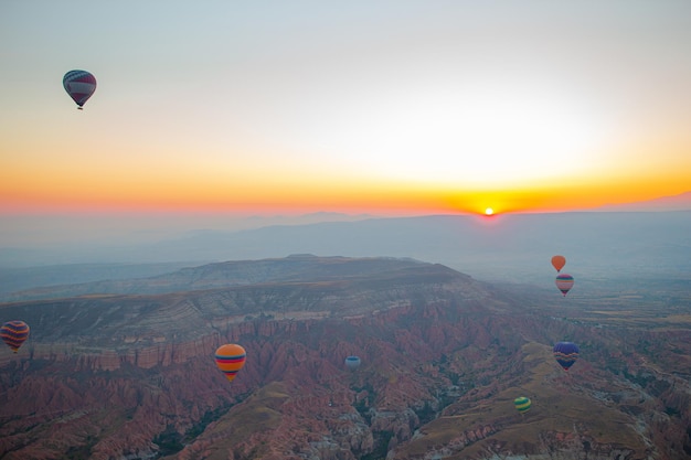 Heteluchtballon vliegt over rotsachtige landschappen in Cappadocië, Turkije