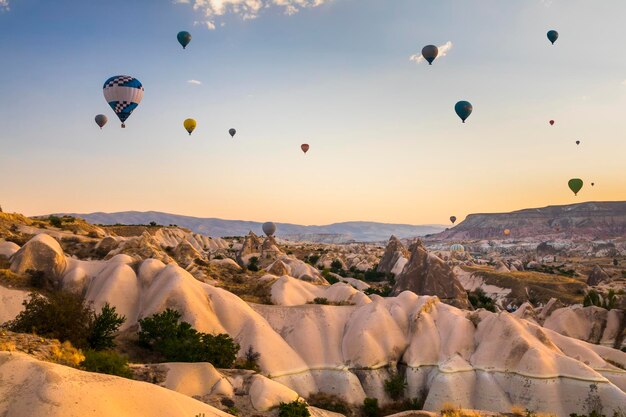 Foto heteluchtballonnen vliegen over een vulkanisch landschap in cappadocië, turkije