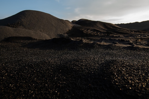 Heuvels van vervuilde, onvruchtbare en giftige donkere grond op uitgestrekt grondgebied met slechte milieusituatie met bewolkte hemel erboven ter illustratie van verlatenheid