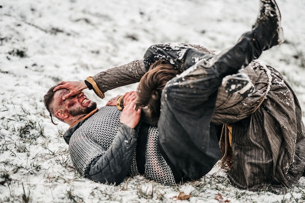 Hevig gevecht van twee jonge krijgers in harnas op de grond in de sneeuw zonder wapens