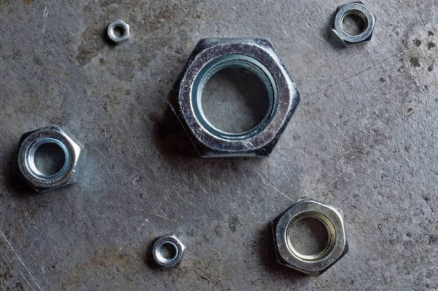 Hex nuts of various sizes spread on a metal surface
