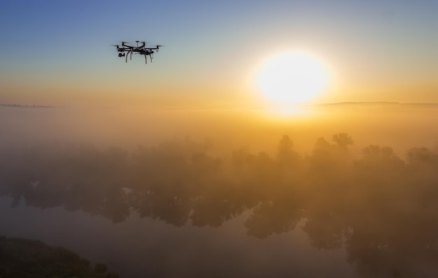 Hexacopter drone over foggy sunrise on river landscape