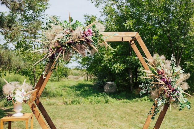 Hexagonal wedding arch with fresh greenery and roses