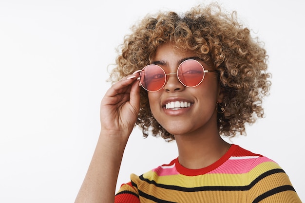 Hey what up, ready for party. Joyful and enthusiastic outgoing african-american attractive woman with blond hair and pierced nose wearing cool sunglasses smiling happily and friendly at camera