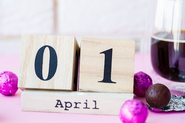 こんにちは春。ピンクの背景に、4月1日付けの木製カレンダー。世界の笑いの日