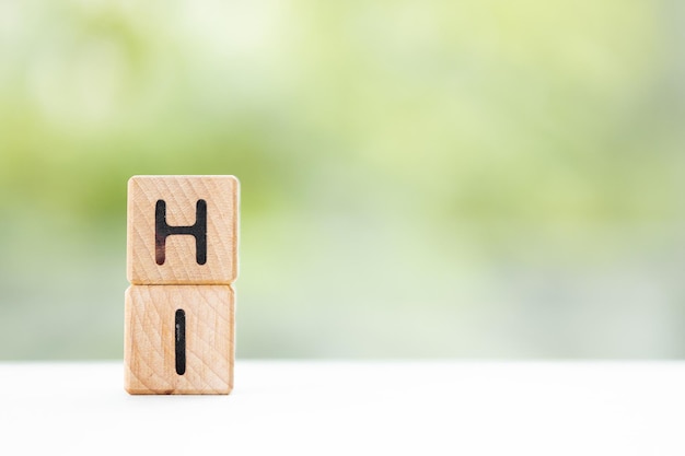 HI word is written on wooden cubes on a green summer background Closeup of wooden elements