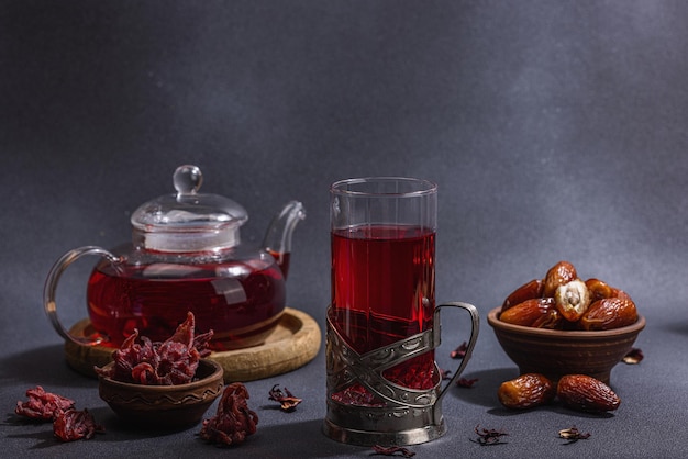 Hibiscus hot tea with dates Traditional Ramadan Kareem concept snack for Iftar or Suhoor meal on dark stone concrete background An arabian sweet treat hard light dark shadow copy space