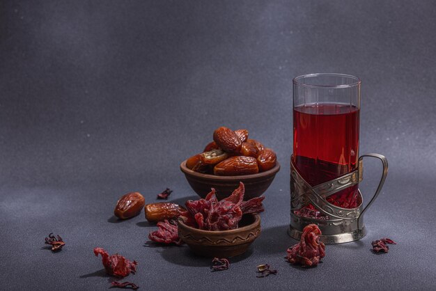 Hibiscus hot tea with dates Traditional Ramadan Kareem concept snack for Iftar or Suhoor meal on dark stone concrete background An arabian sweet treat hard light dark shadow copy space