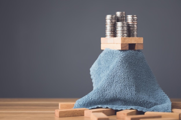 Hidden about risks in business or financial Idea to keep risky as secret Businessman using cloth to cover over tower wooden block stacking game on wooden desk in office