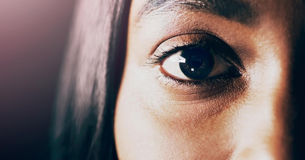 Hidden in plain sight Closeup shot of a beautiful young womans eye against a dark background