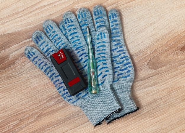 Hidden wiring detector, screwdriver tester and protective gloves out on the table