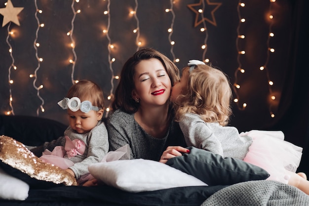 Hield van de jonge moeder die werd gekust door haar schattige dochtertje terwijl ze op bed lag in de buurt van een baby