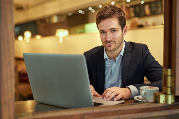 Hier kan ik mijn beste werk doen Portret van een jonge zakenman die zijn laptop gebruikt terwijl hij in een coffeeshop zit