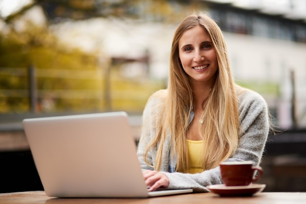 Hier schrijf ik mijn beste blogs Portret van een aantrekkelijke jonge vrouw die haar laptop gebruikt in een openluchtcafé