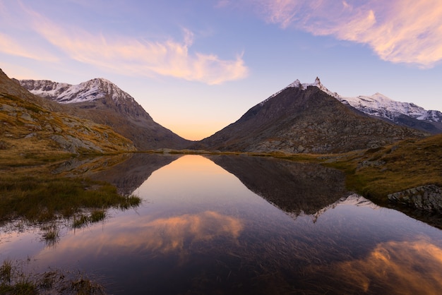 High altitude alpine lake in idyllic land with reflection of majestic rocky mountain