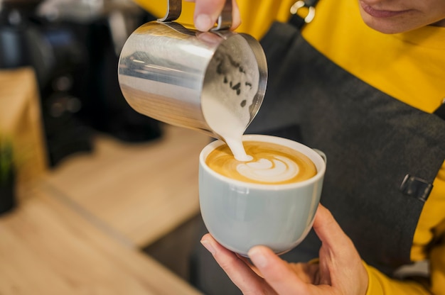 Photo high angle of barista pouring milk in coffee