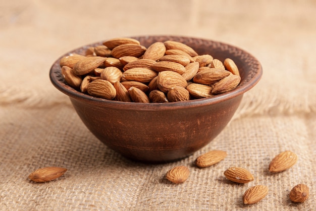 high angle of bowl on burlap with almonds