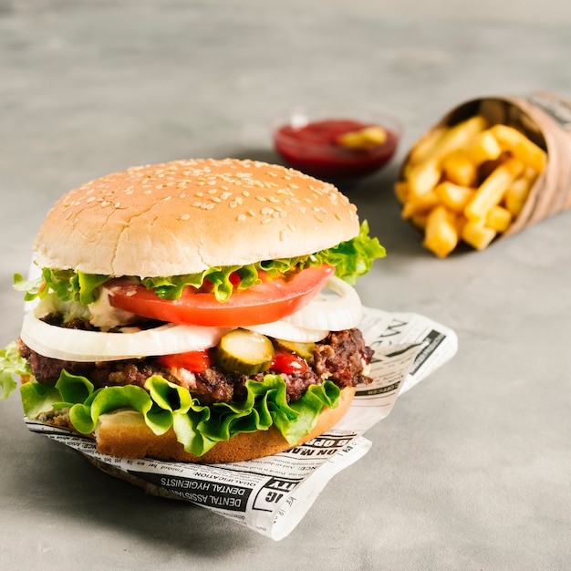 Photo high angle close-up burger with fries on newspaper