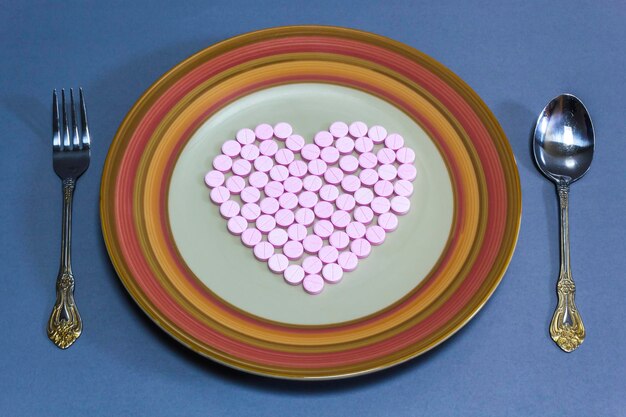 Photo high angle close-up of pink pills arranged in heart shape on plate