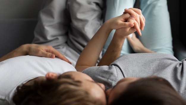 High angle of couple cuddling and holding hands on sofa