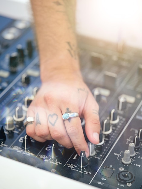 High angle of crop unrecognizable male DJ with tattoos playing music with DJ mixer