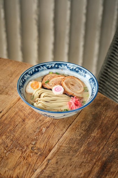 High angle of delicious ramen with pork and egg served in bowl on wooden table in Asian restaurant