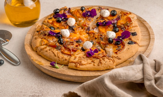 High angle of delicious slice of pizza with blueberries and flower petals