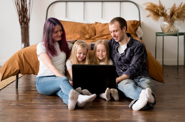 Foto famiglia dell'angolo alto che esamina computer portatile