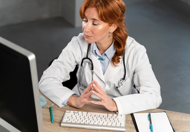 Foto elevato angolo di donna medico guardando il computer sulla sua scrivania