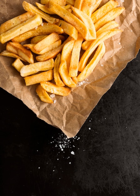 High angle of french fries on paper with salt