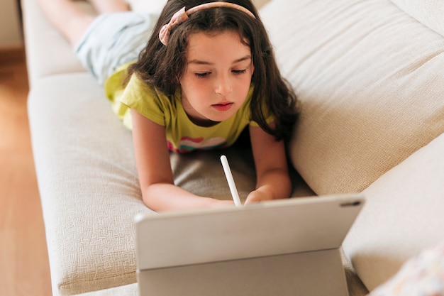 Photo high angle girl with pen looking at her tablet