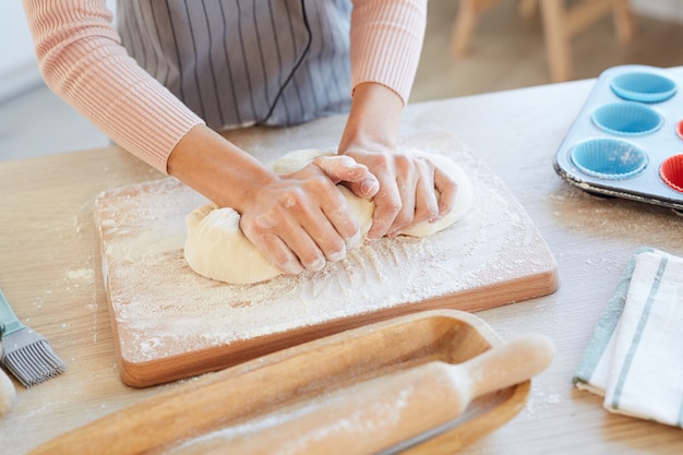 カップケーキの木製のキッチンボードにパン屋の生地をこねる女性の手の高角度の水平方向のショット