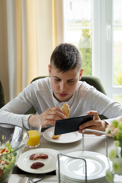 High angle kid eating with smartphone