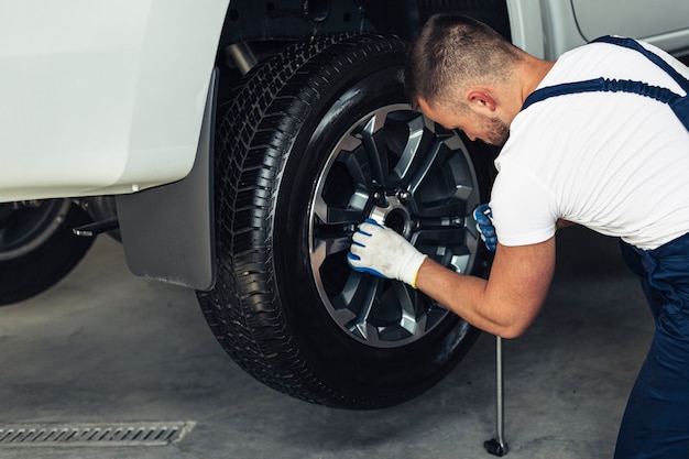 Photo high angle male mechanic replacing wheel