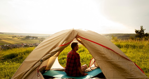 Foto uomo dell'angolo alto in tenda di campeggio